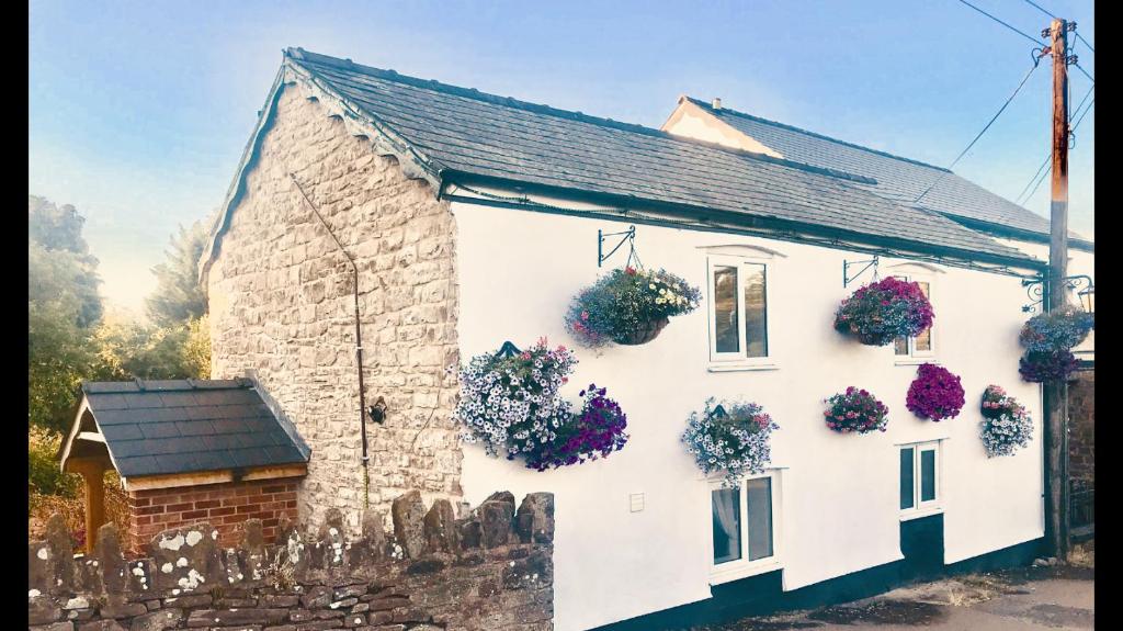 a white house with flowers on the side of it at Brewery Lodge in Blakeney