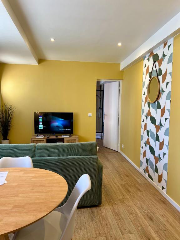 a living room with a green couch and a table at La Cabine ménage et linge inclus in Dieppe