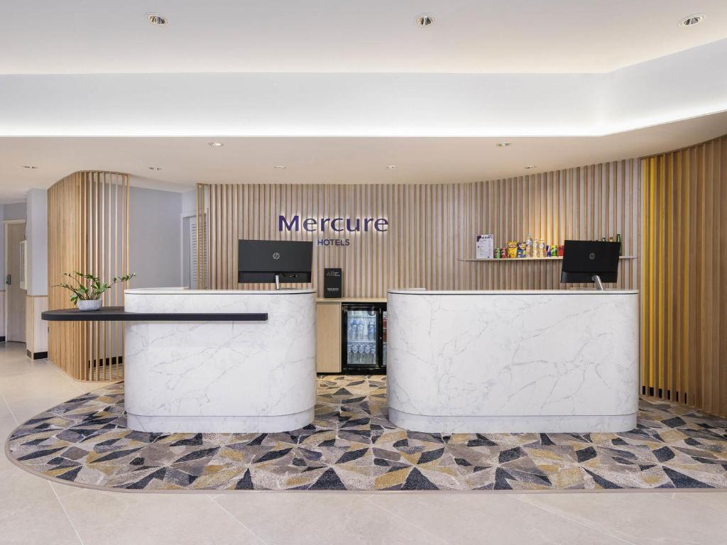 a hotel lobby with a reception counter and ametric sign at Mercure Rockhampton in Rockhampton