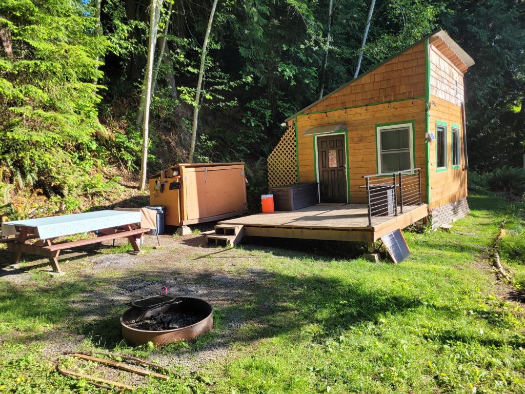 a small cabin with a deck and a fire pit at Moss Haven on Hood Canal in Quilcene