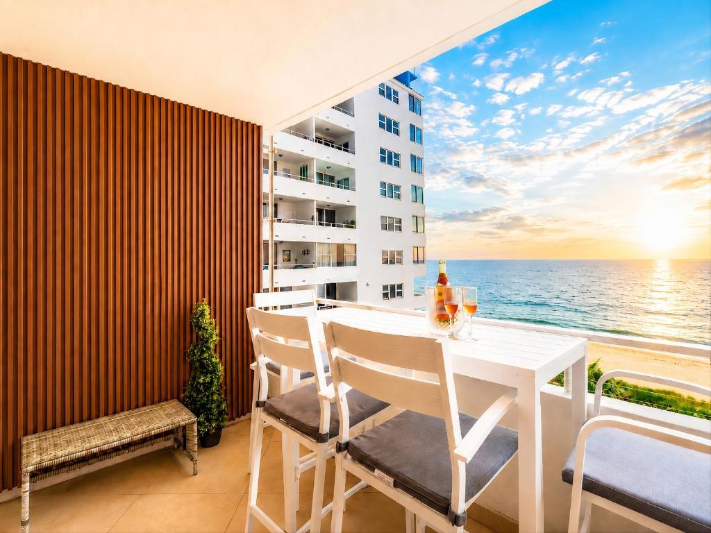 a balcony with a table and chairs and the ocean at Beachfront Condo with Pool, Balcony & Ocean Views in Fort Lauderdale