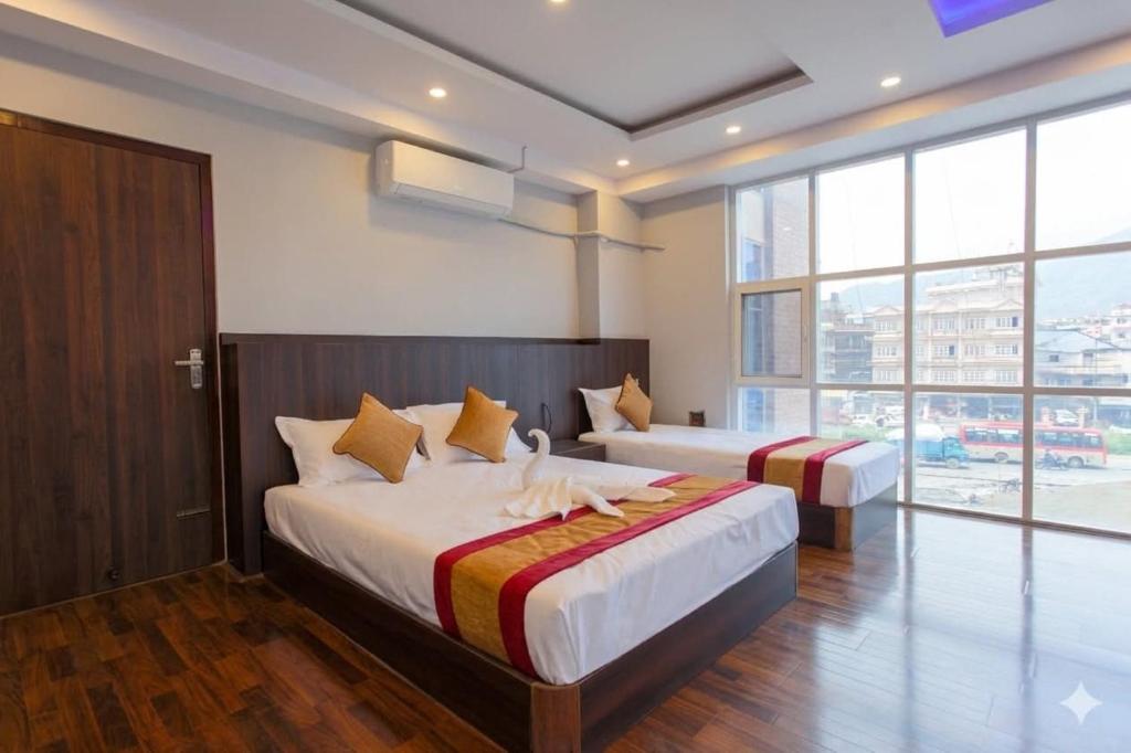 a bedroom with two beds and a large window at Hotel In N Out in Kathmandu