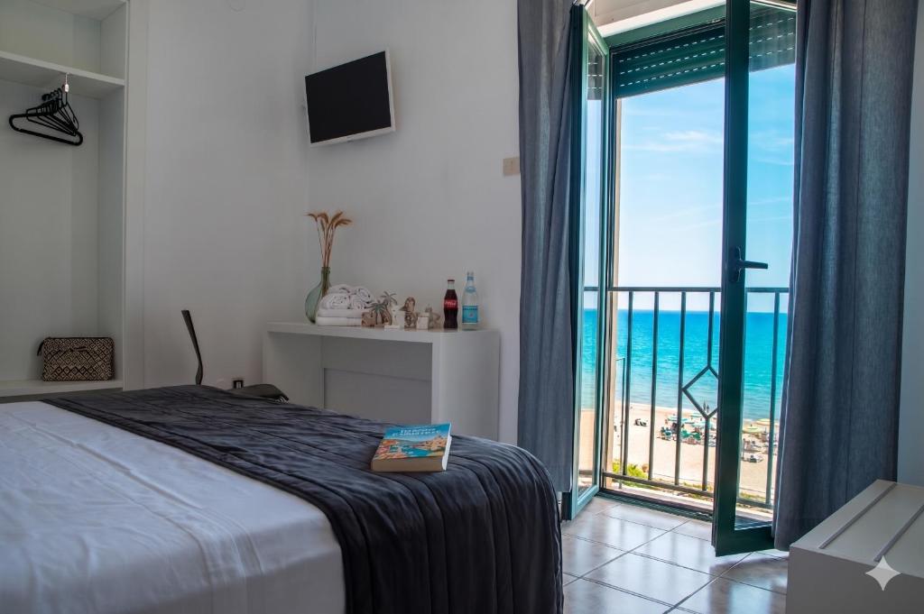 a bedroom with a bed and a view of the ocean at Baron Beach Hotel in Scauri