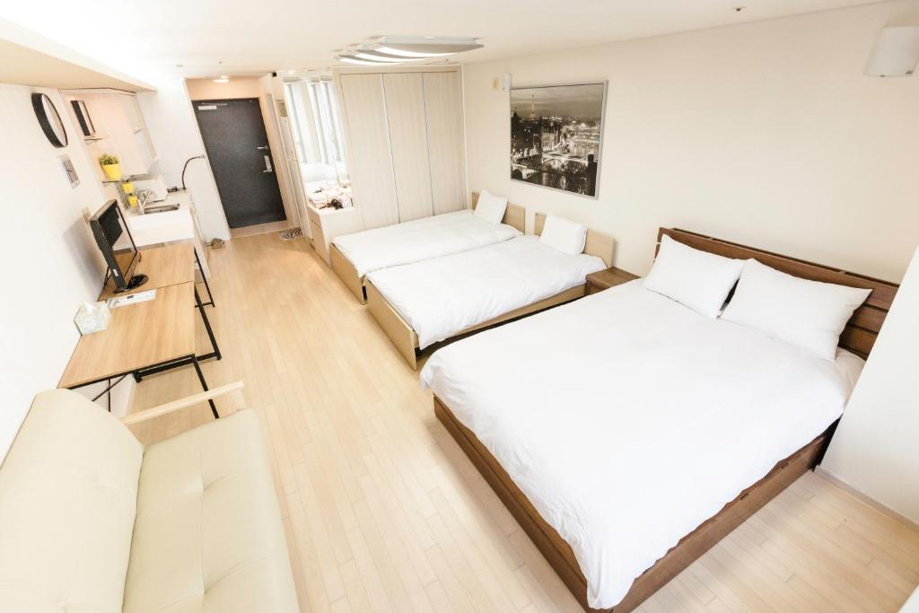 a small room with two beds and a desk at Incheon Airport Egarak Residence in Incheon