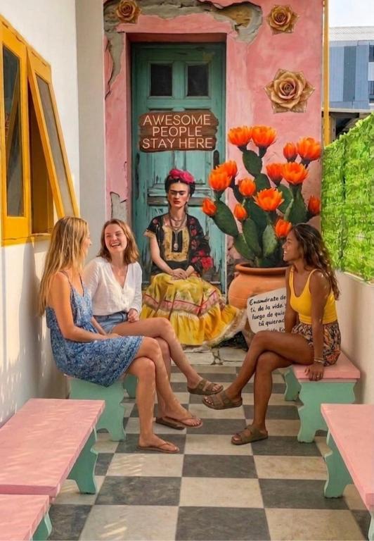 a group of women sitting on benches in front of a house at Decasa Female House in Malang