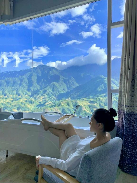 a woman laying in a bath tub in front of a window at Terravia Hotel Sapa Moutain View in Sapa