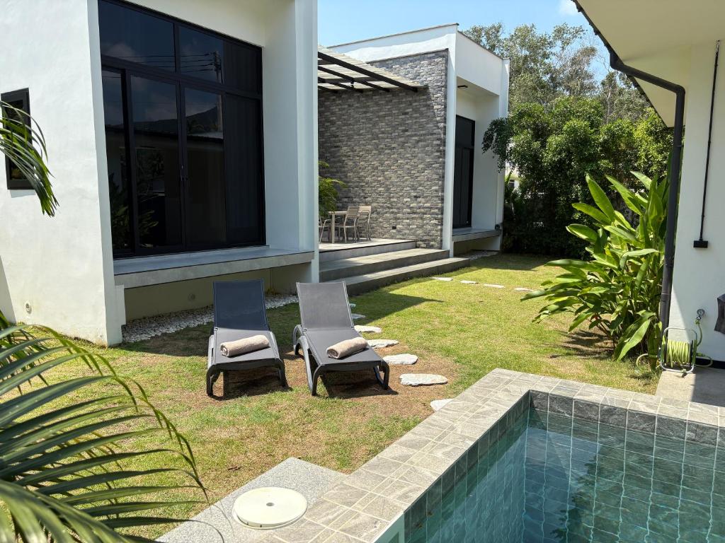 two chairs and a swimming pool next to a house at Noir Blanc Modern Villa in Ko Phangan