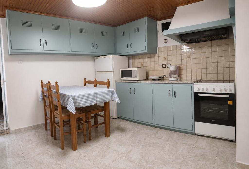 a kitchen with blue cabinets and a table and chairs at Τα σπίτια στα Λειβάδια - Γαρδένια in Vrakhnós
