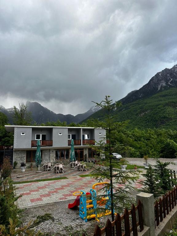 a building with a playground in front of a mountain at Trojet e Mija in Theth