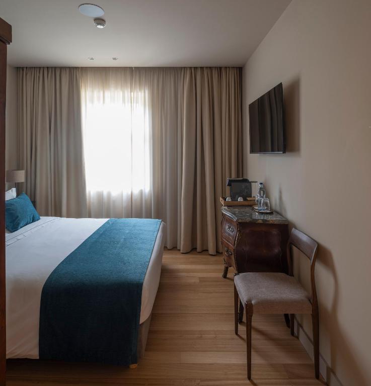 a hotel room with a bed and a desk and a window at A Casita Clara in Amarante