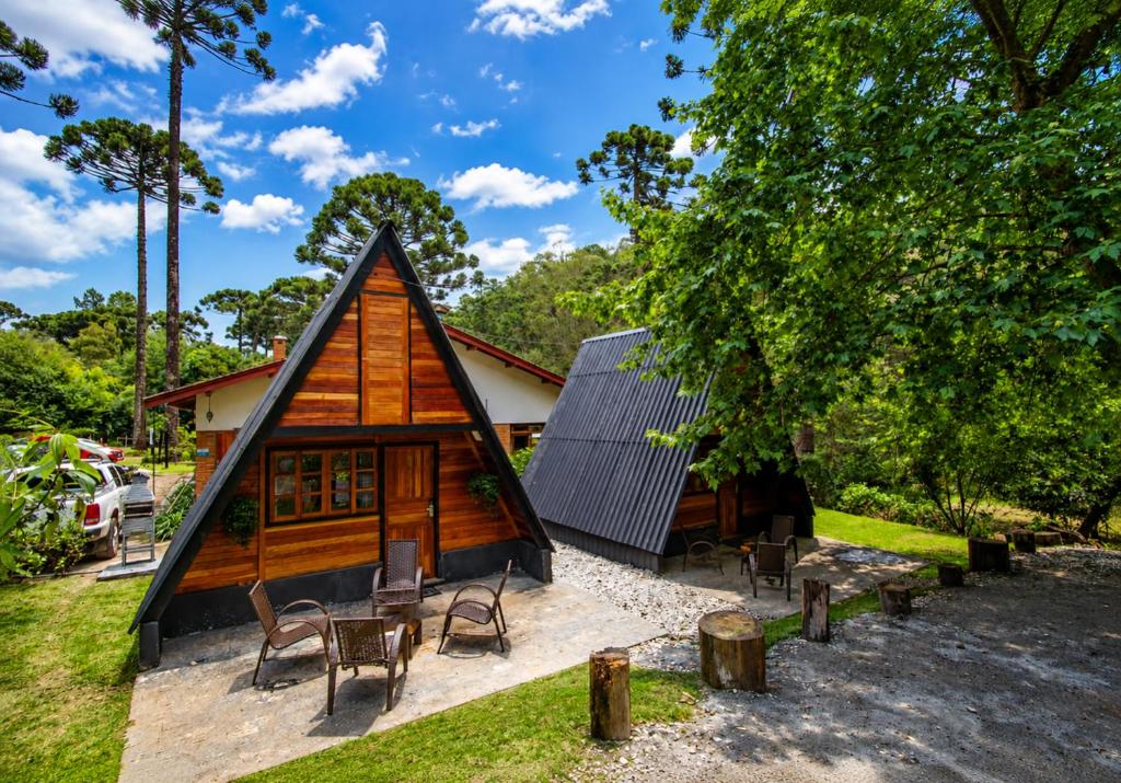 a small cabin with chairs and tables in front of it at Empório reserva da serra - Opções de chalés e Hidromassagem in Campos do Jordão
