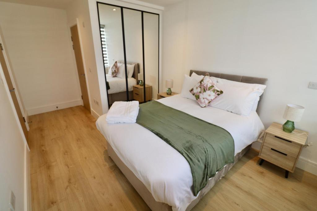 a bedroom with a large bed and a mirror at Chertsey Modern 2-Bed Flat with Parking in Chertsey