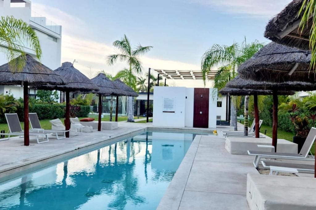 a pool at a resort with chairs and umbrellas at 2bd Tulum Country ClubPGA golfMid termgrocery in Akumal
