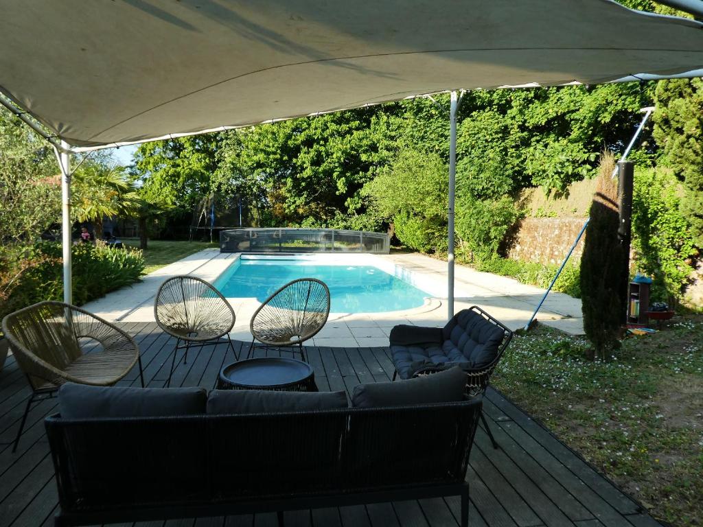 a patio with a couch and chairs under an umbrella at La Closerie DAUVILLIERS in Roinville