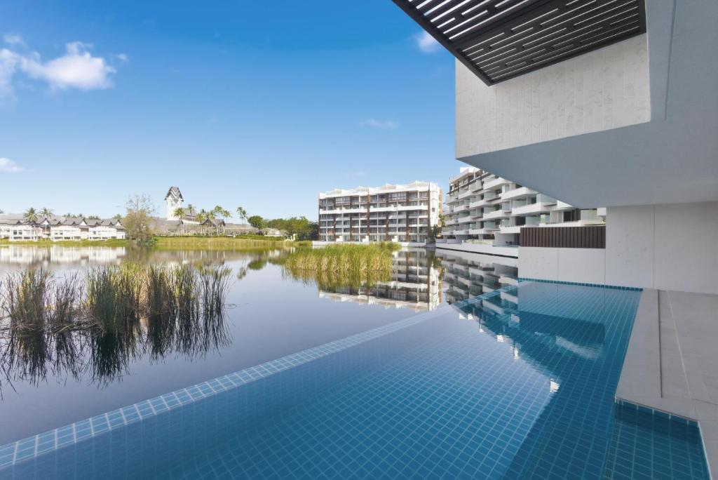 a swimming pool in front of a building with a lake at Laguna luxury apartment - Bang Tao - lake view in Bang Tao Beach