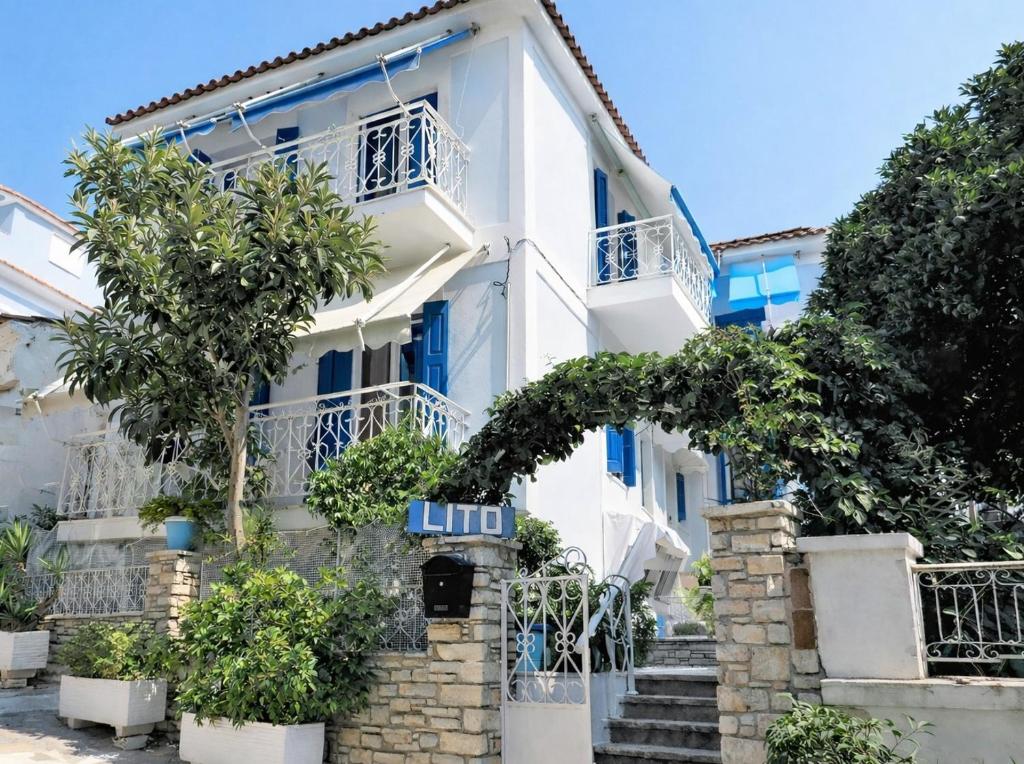 a white house with blue windows and trees at LITO STUDIOS APARTMENTS in Pythagoreio