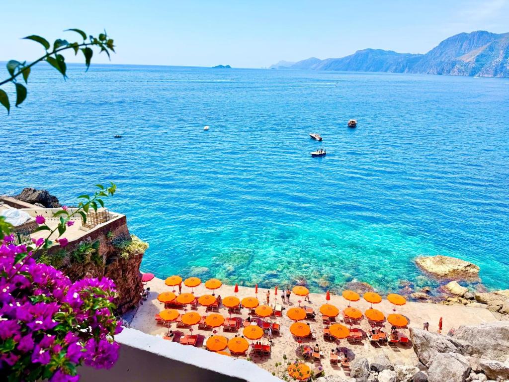 a group of tables with umbrellas in the water at Suite Luna in Praiano