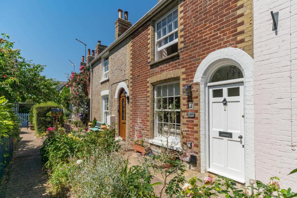 a brick house with a white door and a garden at Christmas Cottage in Yarmouth