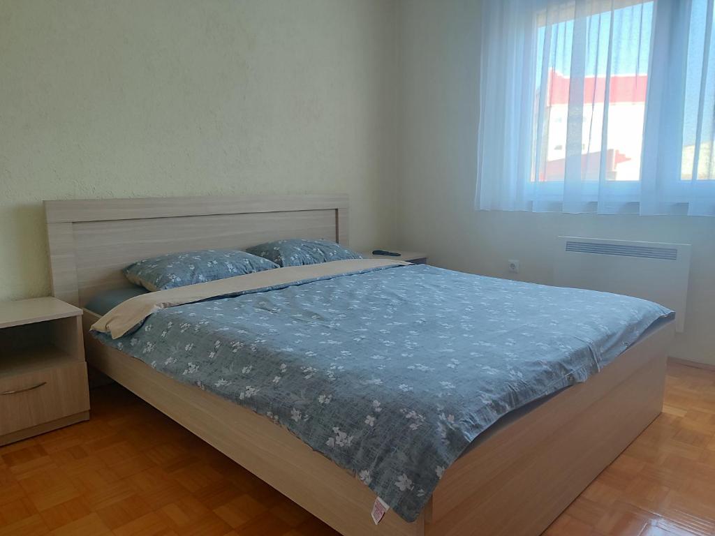 a bedroom with a bed with blue sheets and a window at Apartman Mimi in Bratunac