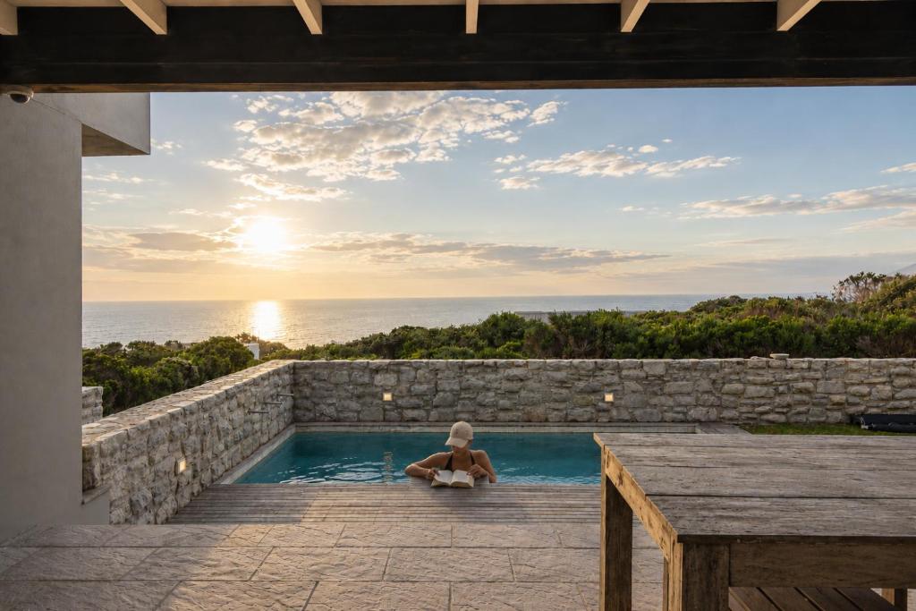 a woman sitting in a swimming pool looking out at the ocean at Peninsula Villa - Romansbaai in Gansbaai