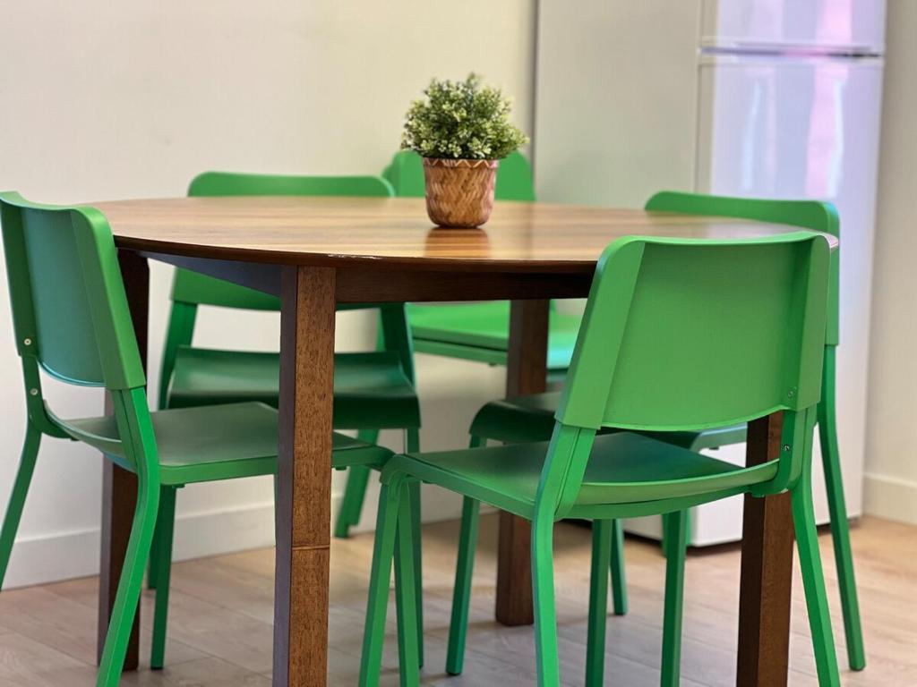 a wooden table with green chairs and a potted plant at Appartement 2 - Est in Rimouski