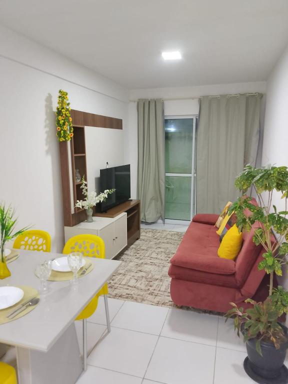 a living room with a red couch and yellow chairs at Apto Tropical - Enseadas dos Corais in Cabo de Santo Agostinho