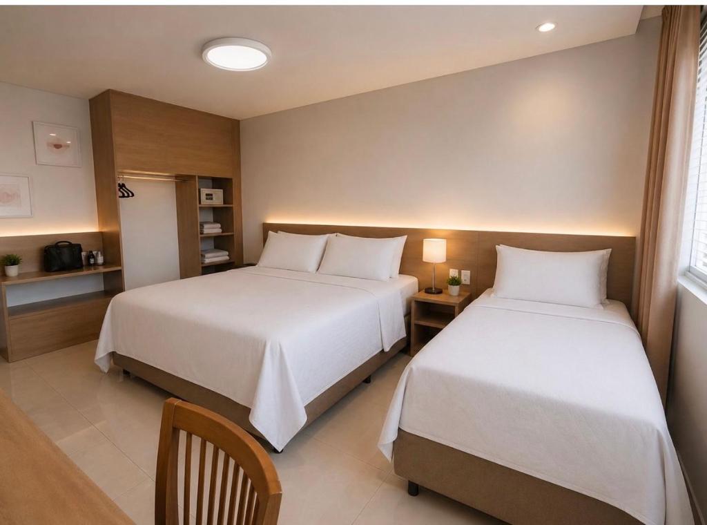 a hotel room with two beds and a table at Flat hotel Blue tree no adrianopolis Até 4 pessoas in Manaus