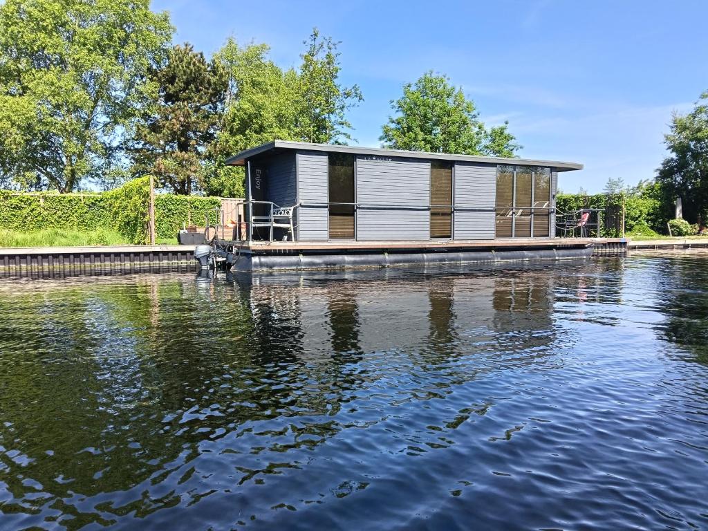 a house on the water with a building at Houseboat Enjoy with 200m Private Garden on the Lake in Vinkeveen