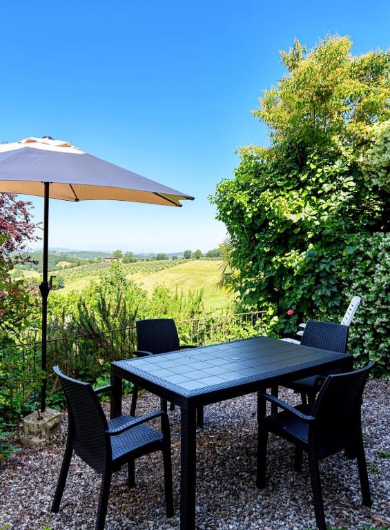a black table and chairs with an umbrella at Casa Maddalena in Monteriggioni