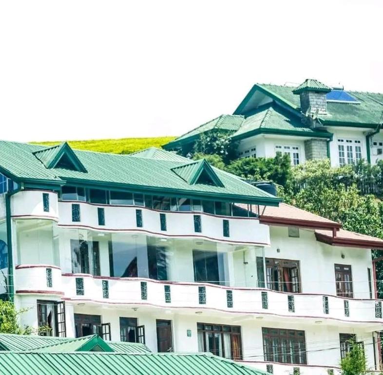 a large white building with a green roof at Breeze Mahagedara in Nuwara Eliya