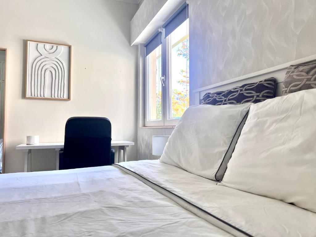 a bedroom with a bed and a chair and a window at Quarto confortável in Amadora