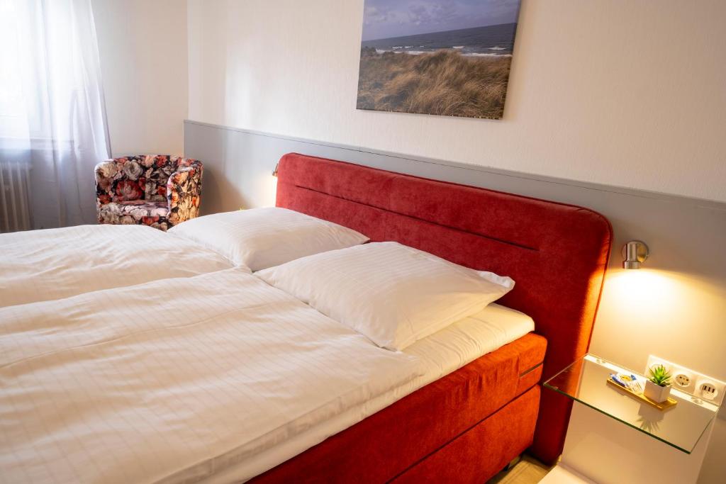a bed in a bedroom with a red headboard at Mühlenkamp Hotel & Gastronomie in Oelde