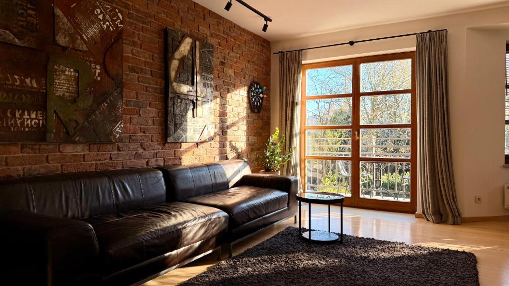 a living room with a leather couch and a brick wall at Apartament Widna in Krakow