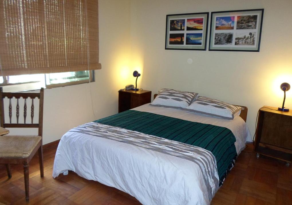 a bedroom with a bed and a chair and two lamps at Pascua 2-baño compartido in Santiago