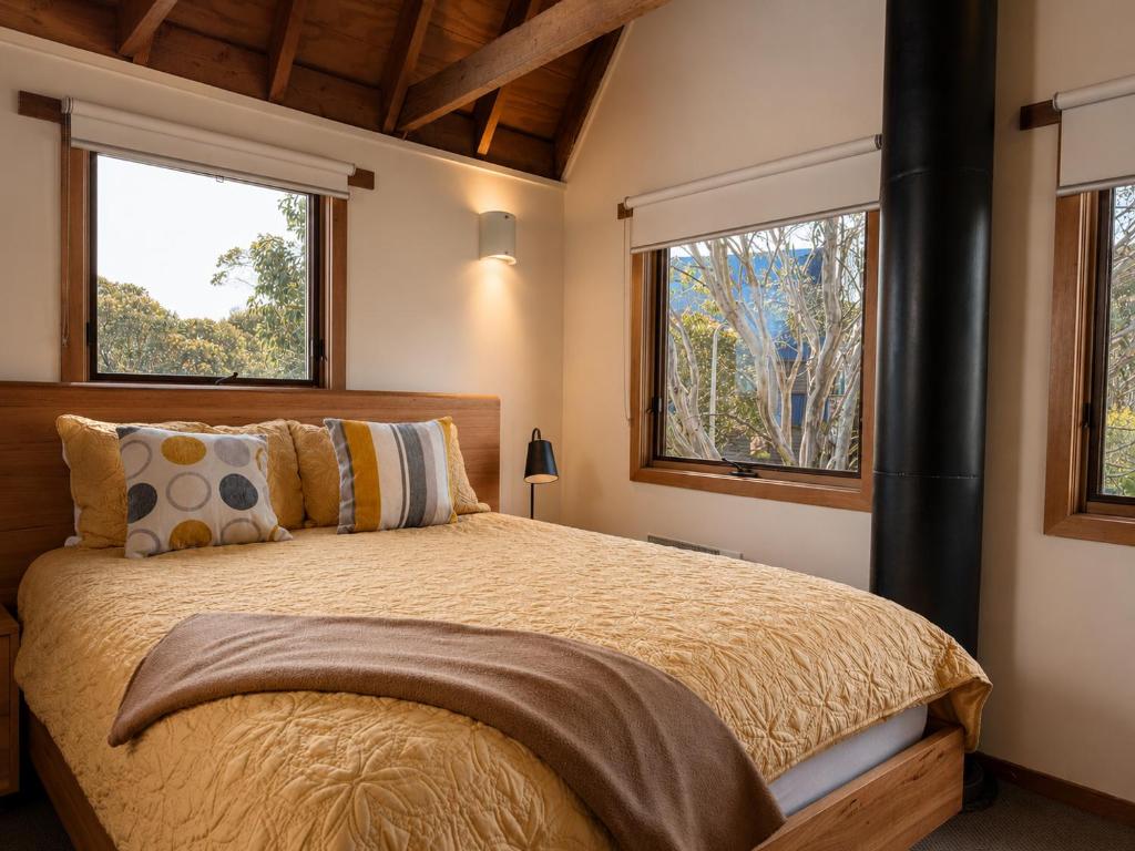 a bedroom with a large bed and two windows at Brindabella Chalet alpine-getaways in Dinner Plain