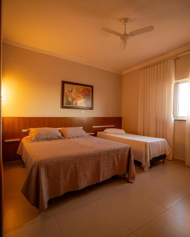 a bedroom with two beds and a ceiling fan at Souza Apart 1 - Apartamentos completos com muito aconchego in São Thomé das Letras