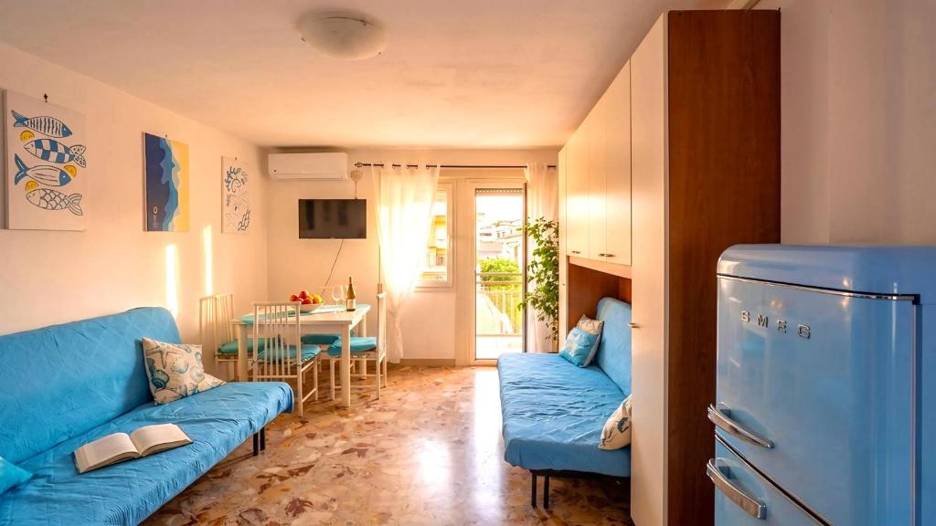 a living room with a blue couch and a table at Casa vacanza 'Note di mare' in Torvaianica