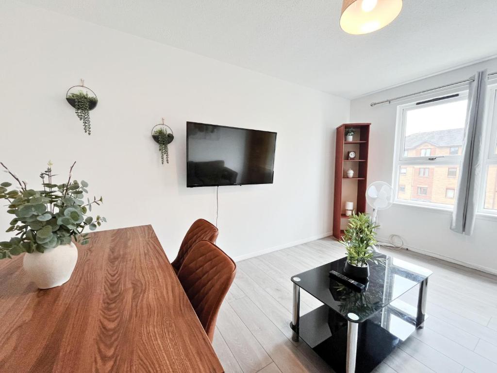 a living room with a table and a tv on a wall at The Easter Suites with free parking in Edinburgh