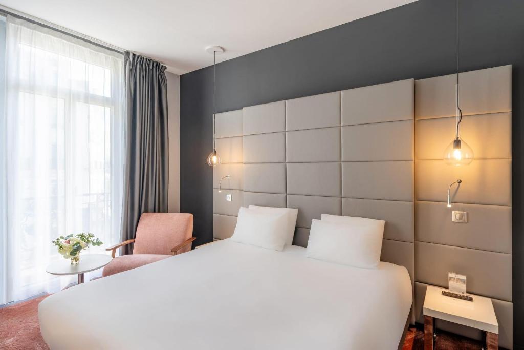 a hotel room with a white bed and a chair at Best Western Dijon Centre Gare in Dijon