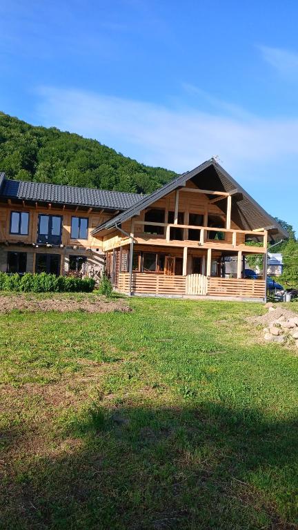 a large wooden house with a field in front of it at Садиба Федорчуків За рікою1 in Sheshory