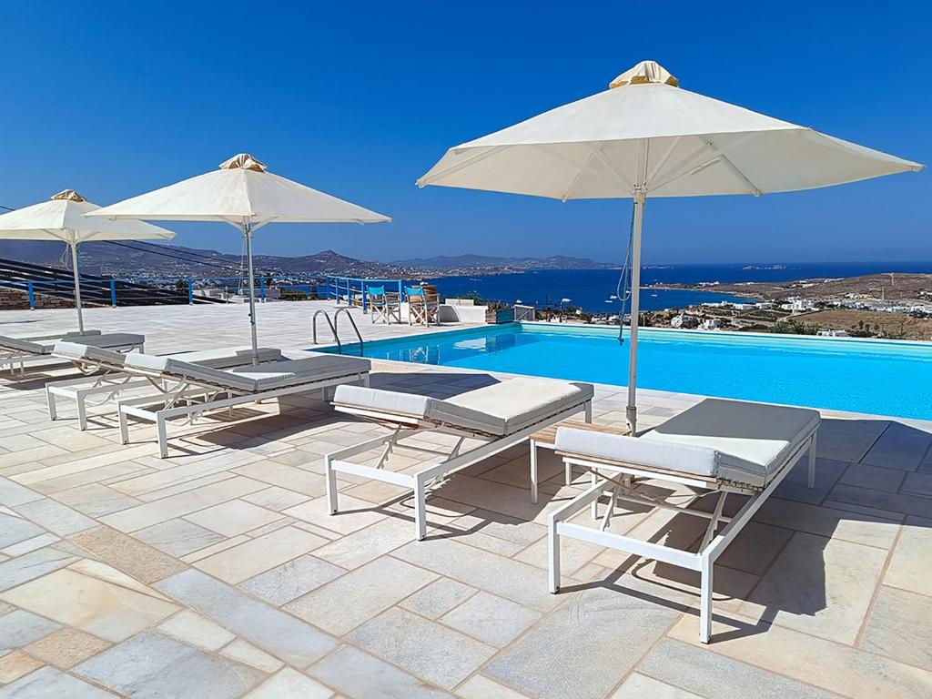 a group of chairs and umbrellas next to a swimming pool at White Blue Houses & Apartments Paros in Parikia