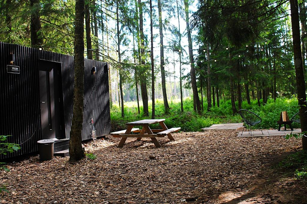 a picnic table and a bench in the woods at PRIVAATNE Metsamajake SAUNAGA "VULIN" in Sigula