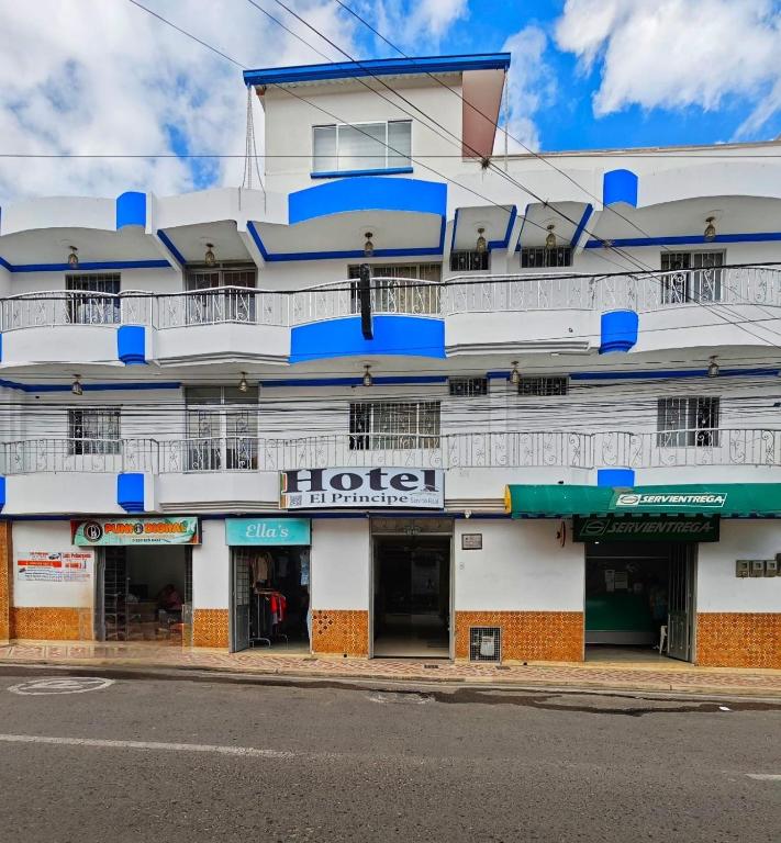 a white building with blue balconies on a street at Hotel El Principe in Ocaña
