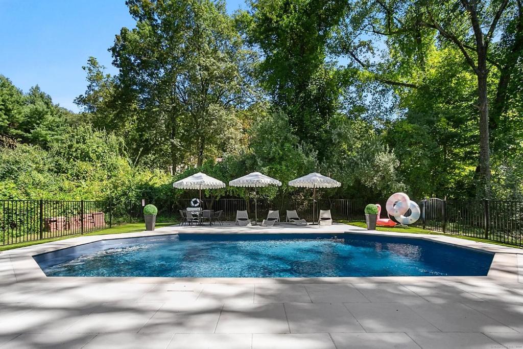 a swimming pool with chairs and umbrellas in a yard at Renovated Retreat with Heated Pool in Redding