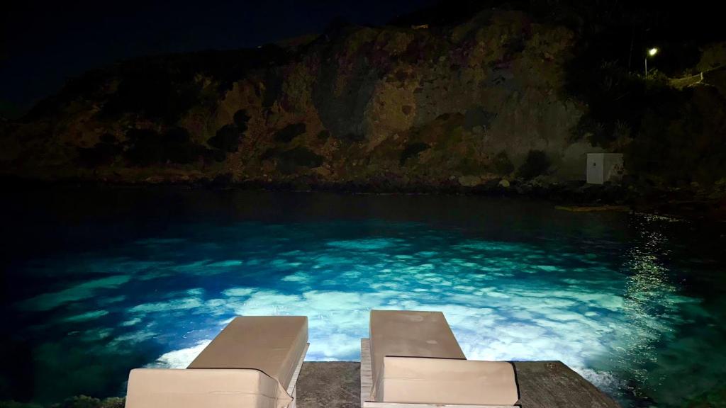 two lounge chairs in a swimming pool at night at Milos Boathouse-BETWEEN2SEAS VIEW-STUNNING SUNSET VIEW in Kástron