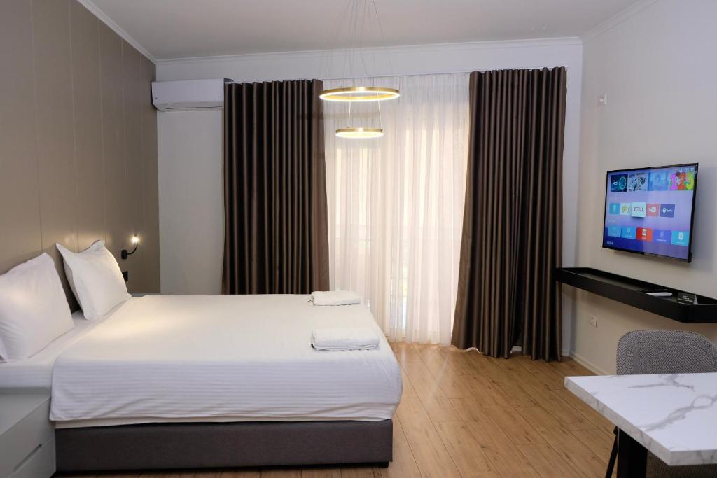 a hotel room with a bed and a flat screen tv at Centralin Apartotel in Tirana