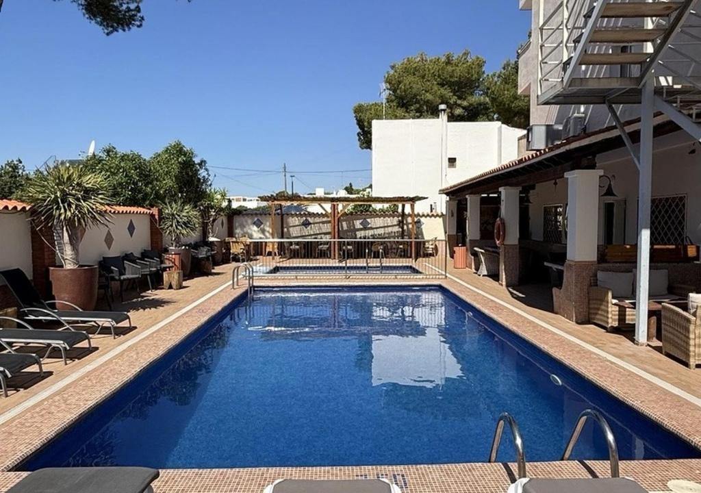 a large blue swimming pool next to a building at El Cortijo Escana in Es Cana