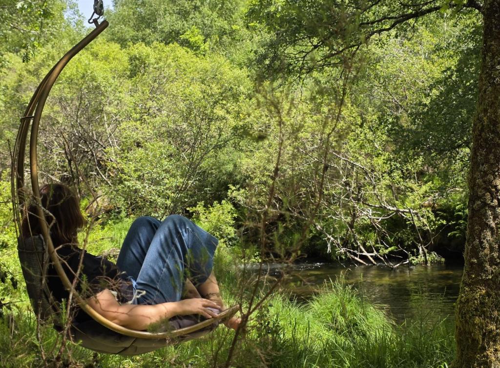 a person laying in a hammock in a river at Moinhos do Poço Verde in Castro Laboreiro
