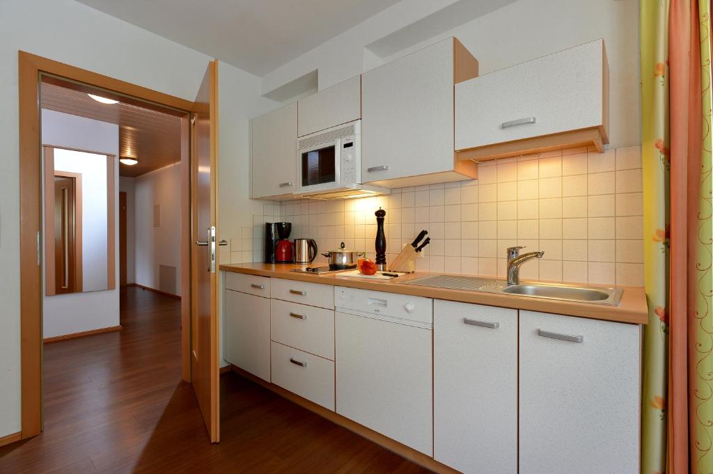 uma cozinha com armários brancos e um lavatório em Villa Amsel em Mayrhofen