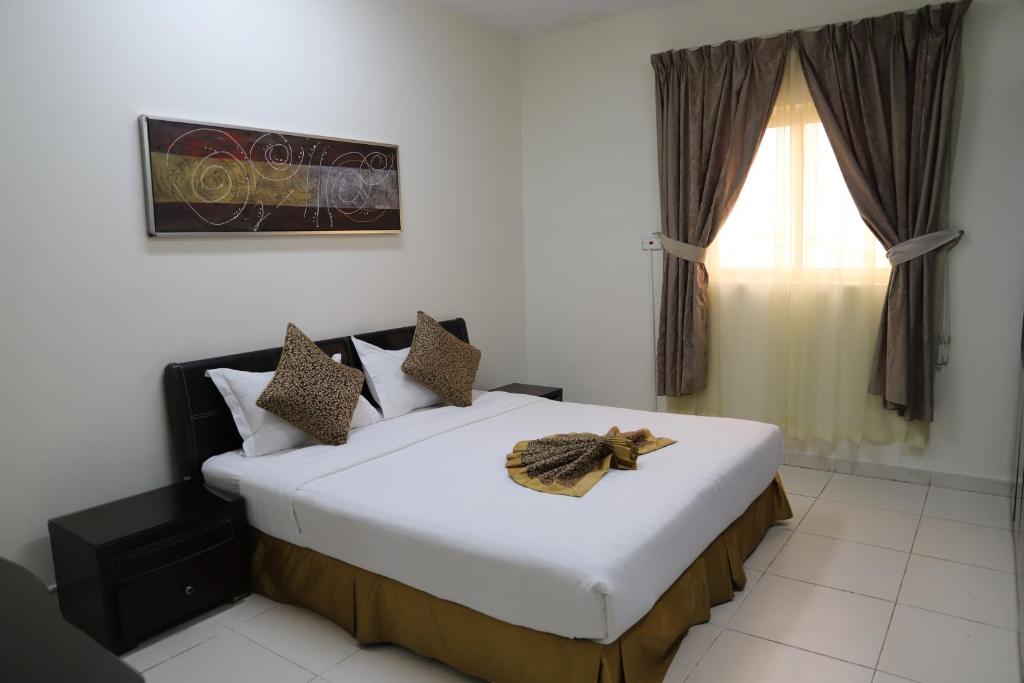 a bedroom with a large white bed with a window at Binayat Hama Serviced Apartments - Standard in Al Jubail